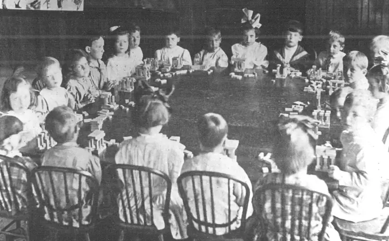 Kindergarten children seated around a table of building blocks, Toledo, Ohio, 1909