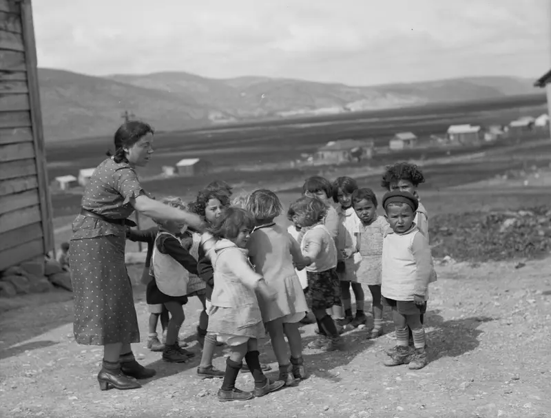 A teacher and very young children in a ring on open ground, Ben Shemen, around 1920